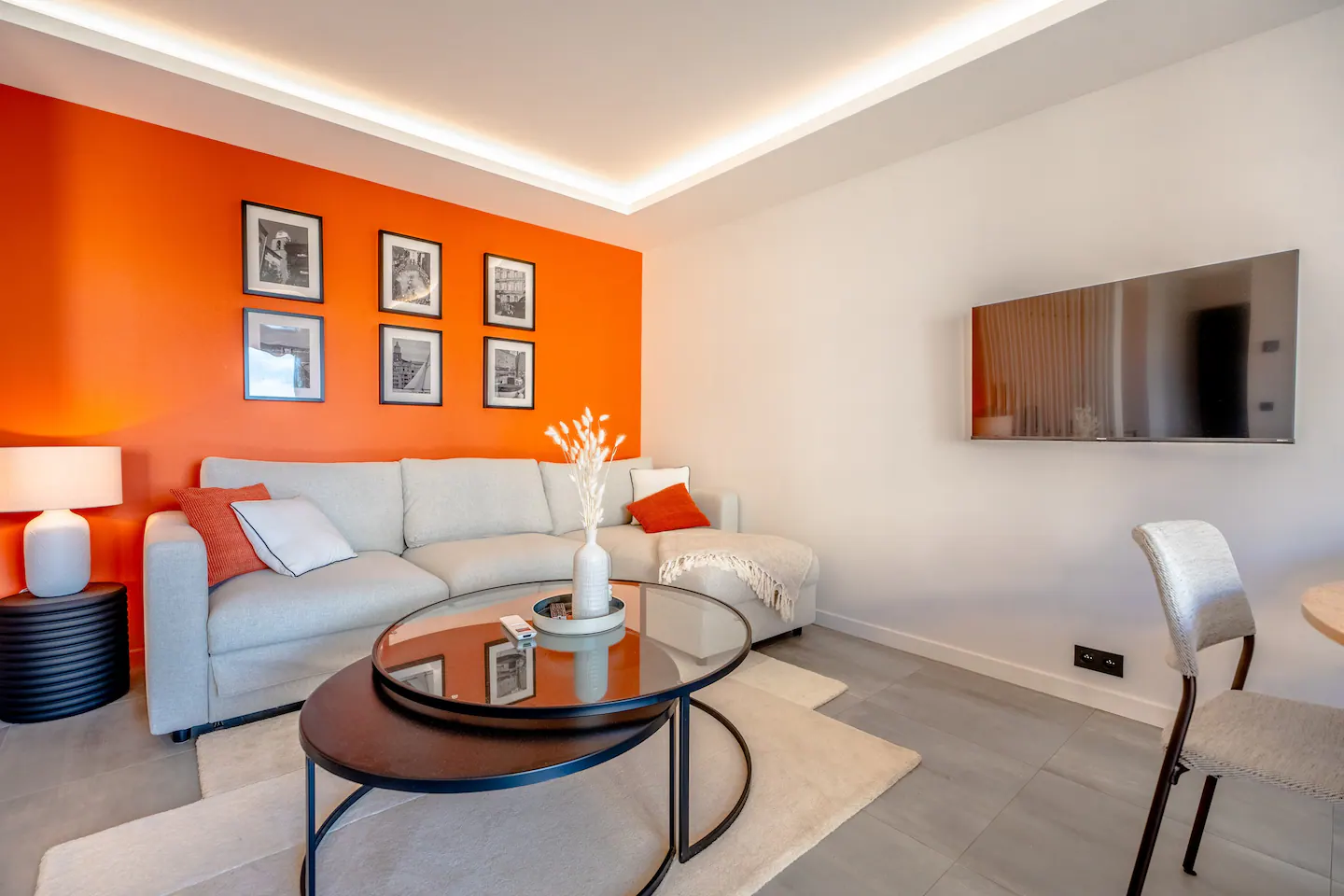 Salon de Lei Amourie avec canapé clair, mur orange et table basse ronde