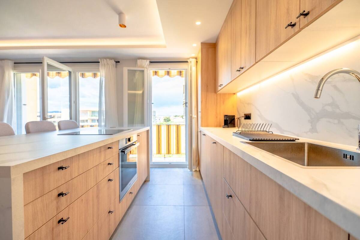 Cuisine lumineuse de Lei Amourie avec menuiseries bois clair et balcon