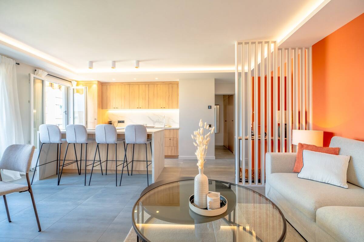 Salon lumineux de Lei Amourie avec cuisine ouverte, claustra blanc et mur orange
