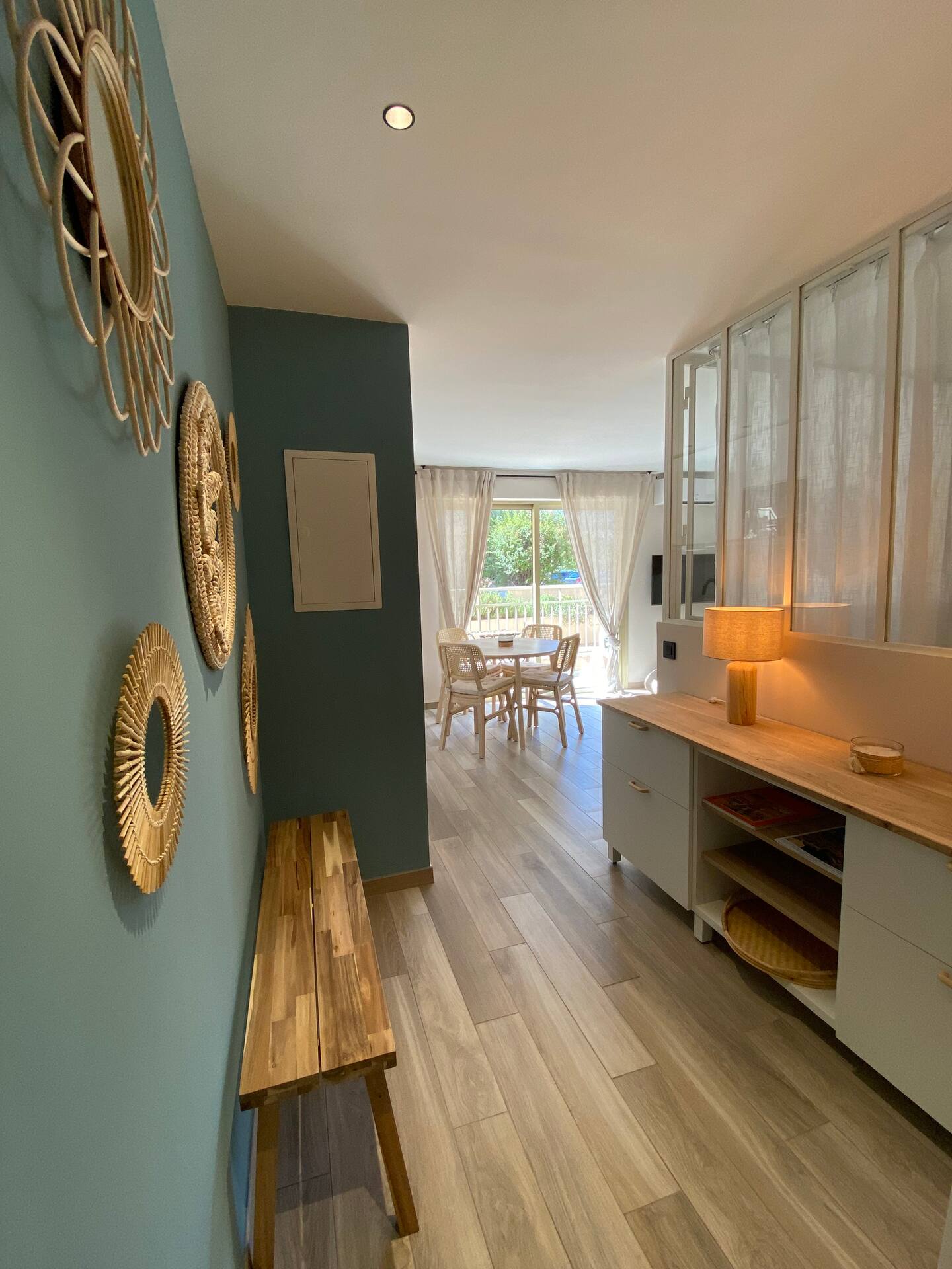 Entrée de l'appartement Petit Prince avec mur bleu, banc en bois et verrière
