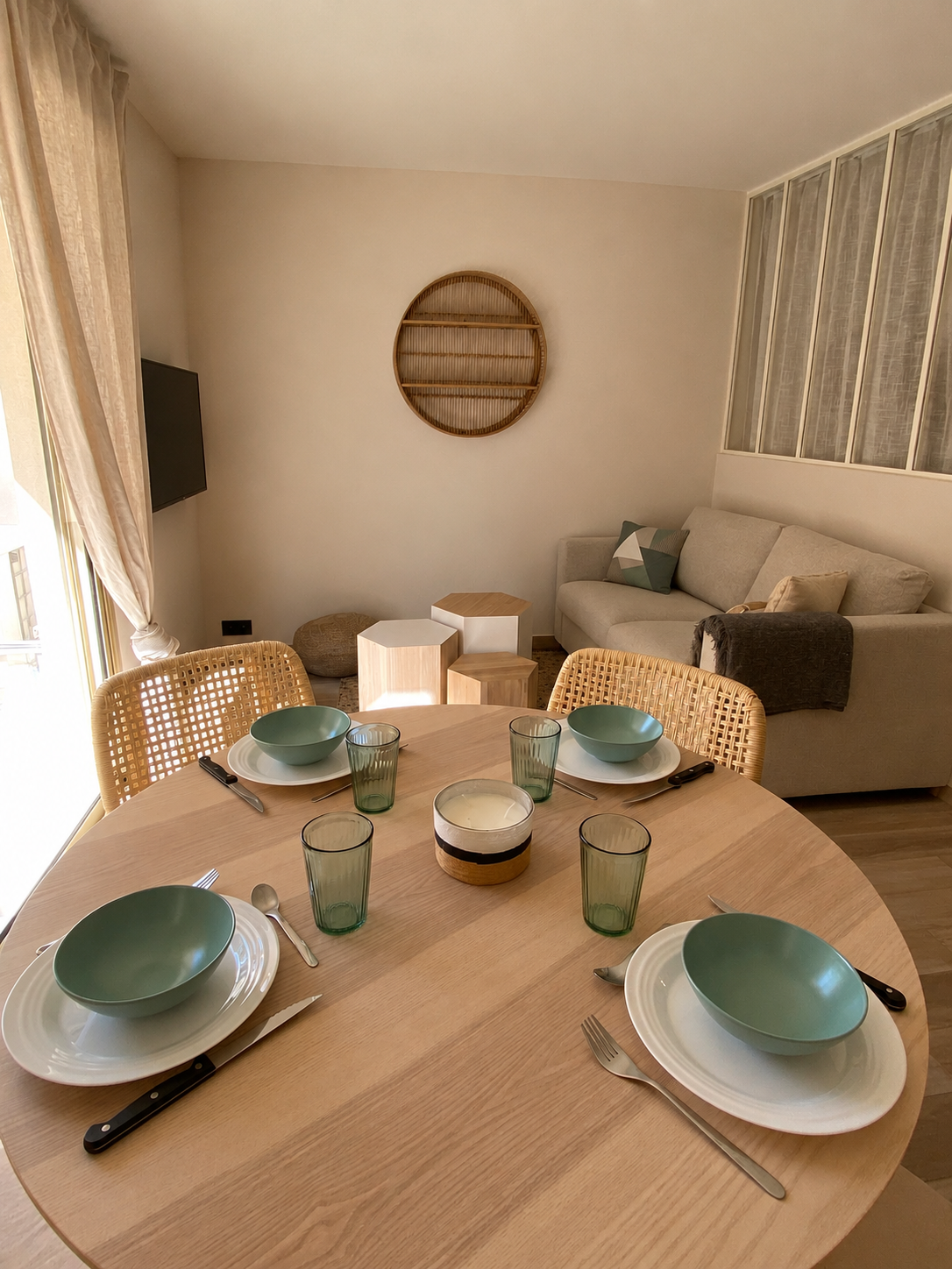 Séjour de l'appartement Petit Prince avec table ronde, canapé clair et matières naturelles