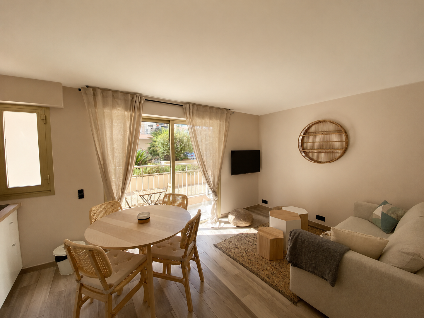 Vue large du séjour de l'appartement Petit Prince avec table ronde, canapé et baie vitrée